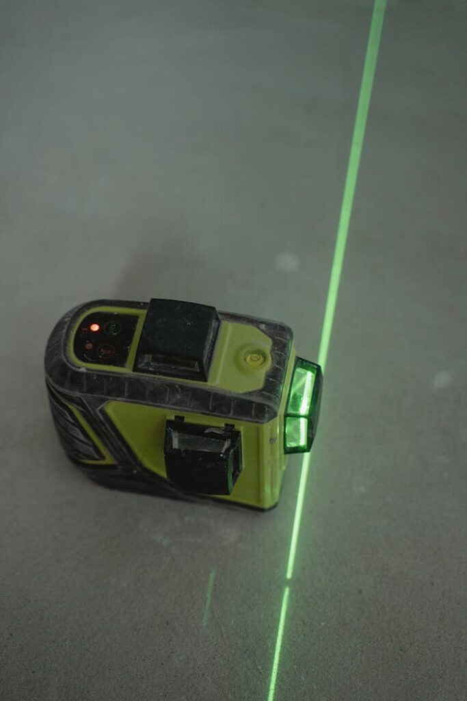 A green laser level projecting a line on a concrete floor for alignment tasks.